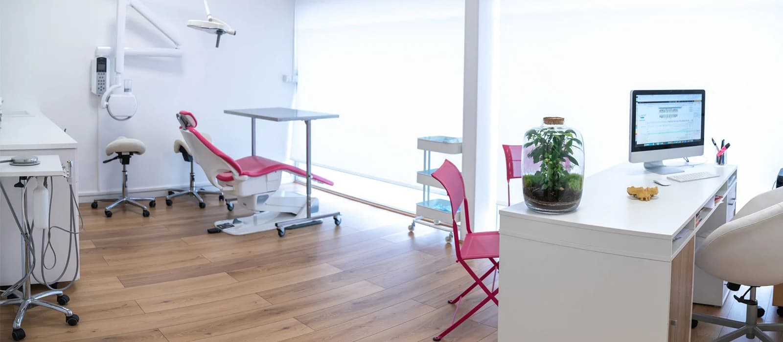 Bright, modern dental treatment room with a pink dental chair